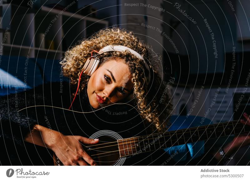 Happy woman playing guitar on floor music headphones listen happy smile musician cheerful instrument guitarist practice hobby acoustic female young melody