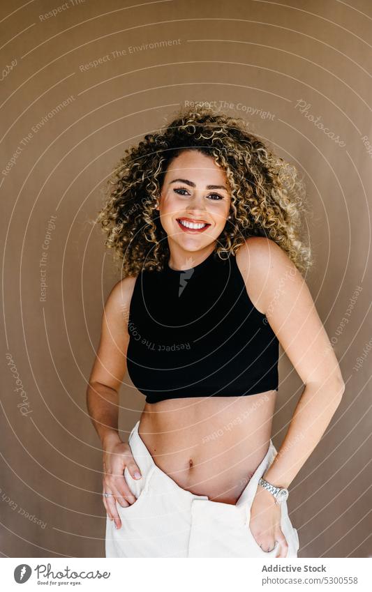 Smiling curly haired woman in studio model studio shot hand in pocket appearance charm personality glance posture smile happy positive toothy smile female young