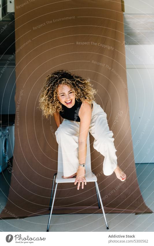 Cheerful woman standing on chair model studio shot carefree laugh fun appearance expressive joy having fun smile cheerful happy positive female young outfit