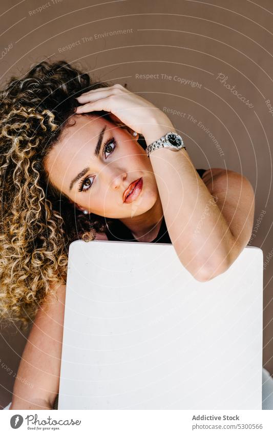 Young attractive woman leaning on white chair model studio shot portrait makeup appearance lean on cube curly hair individuality young unemotional emotionless