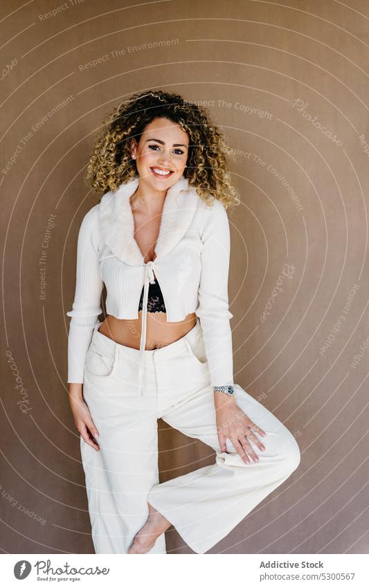 Smiling woman in white clothes against brown background model studio shot carefree appearance pretty curly hair charismatic toothy smile cheerful happy positive