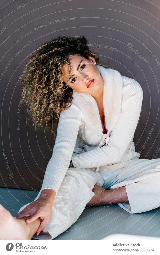 Confident woman in white clothes sitting on floor model studio shot makeup gorgeous charismatic confident self assured appearance individuality young
