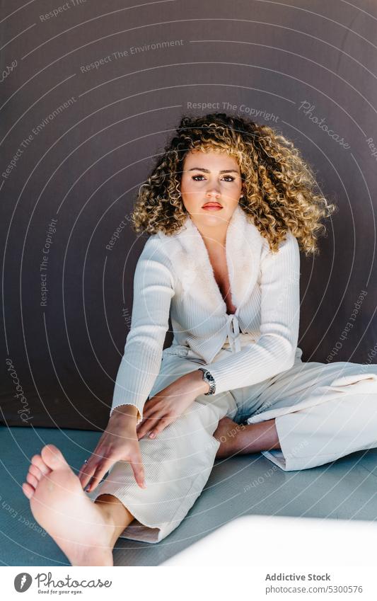 Confident woman in white clothes sitting on floor model studio shot makeup gorgeous charismatic confident self assured appearance individuality young