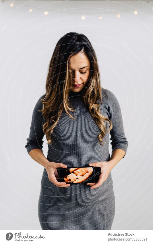 Young pregnant woman with fetus photo belly smartphone garland glow await expect calm style dress female prenatal device gadget wireless connection pregnancy