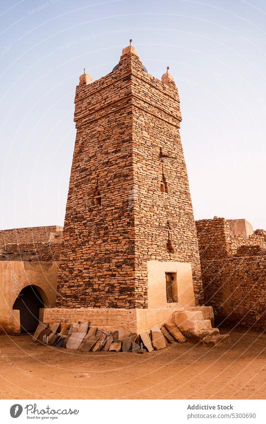 Ancient mosque with stone fence architecture ancient heritage culture historic religion building old aged islam sahara mauritania africa cloudless blue sky