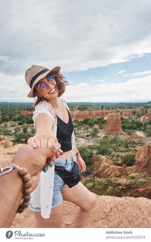 Positive traveler with boyfriend in desert area woman holding hands follow me happy smile love straw hat tourist vacation tatacoa desert colombia couple
