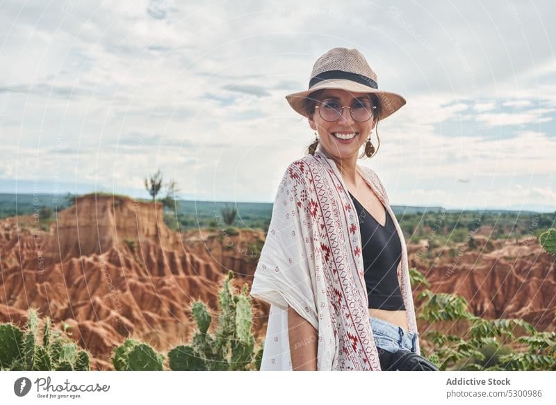 Positive traveler standing in desert area woman happy smile love straw hat tourist vacation tatacoa desert colombia cheerful eyeglasses enjoy middle age female