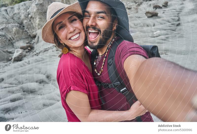 Happy couple taking selfie in canyon tourist self portrait tatacoa desert colombia smartphone happy boyfriend girlfriend hug embrace take photo moment memory