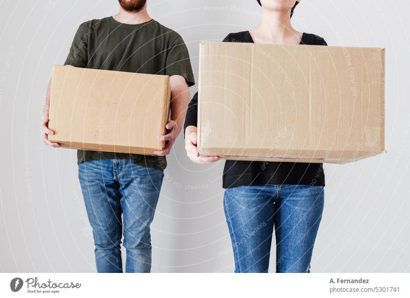 A young woman and man holding cardboard boxes in an empty room. Concept of becoming emancipated and buying a house to live as a couple. Cardboard Cardboard box