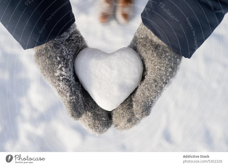 Anonymous person with heart shaped snowball in winter day show demonstrate cold frost nature warm clothes frozen wintertime ground season countryside weather