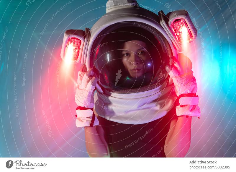 Woman in cosmonaut helmet with neon light woman astronaut model serious confident futuristic portrait appearance style illuminate female glow personality gaze