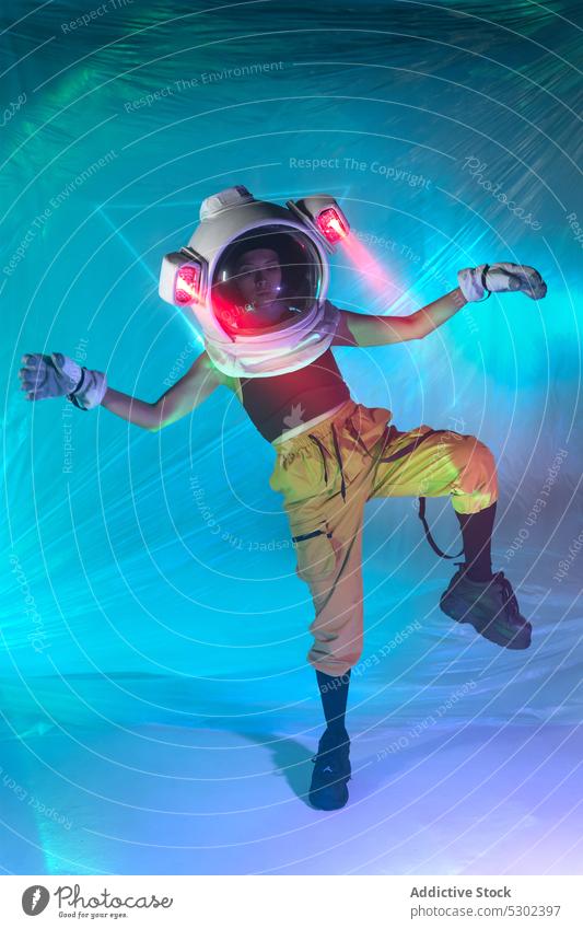 Woman in astronaut helmet dancing on floor woman dance neon cosmonaut style futuristic illuminate energy confident studio female move cool glow young lamp