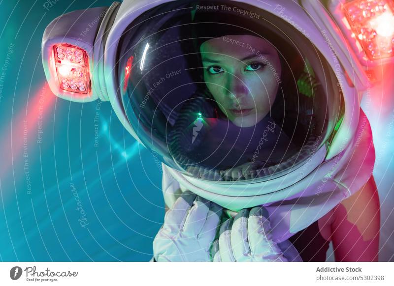 Woman in cosmonaut helmet with neon light woman astronaut model serious confident futuristic portrait appearance style illuminate female glow personality gaze