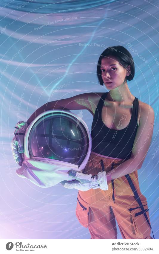 Confident woman with helmet in studio confident portrait serious neon calm protect astronaut cosmonaut futuristic focus thoughtful female young unemotional