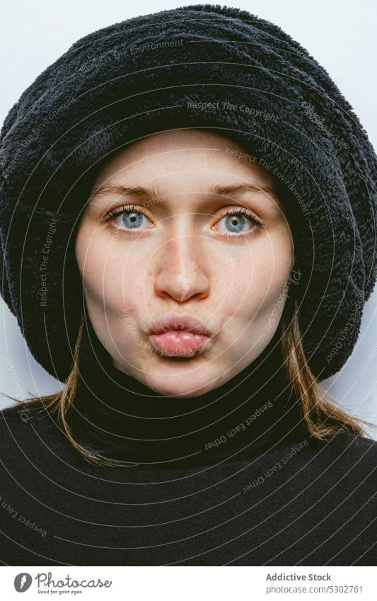 Calm woman showing duck face portrait model pouting lips hat smile content style natural female turtleneck young appearance positive make face happy trendy
