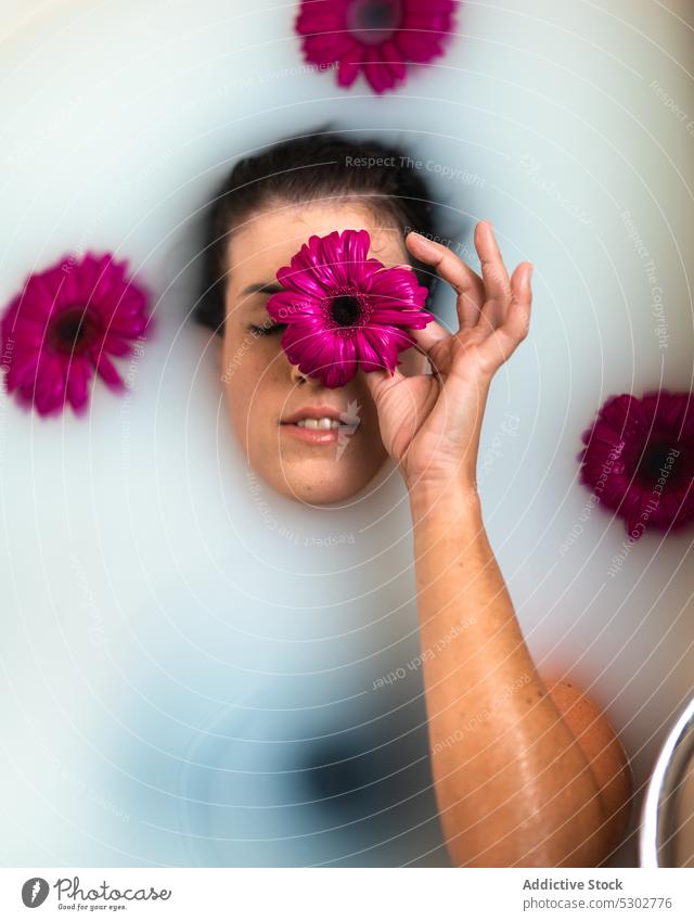 Female covering eye with pink flower while taking bath woman cover eyes milk bathtub routine peaceful leisure hygiene spa female wellness rest chill natural