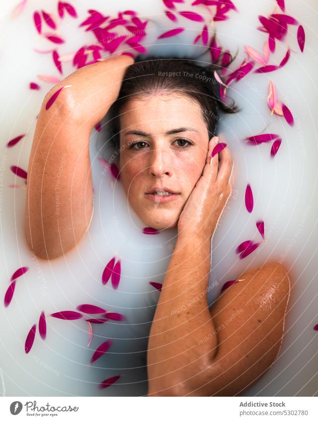 Calm woman taking bath with pink petals and milk flower bathtub peaceful hygiene spa skin care sensual female wellness rest chill natural water fresh wellbeing