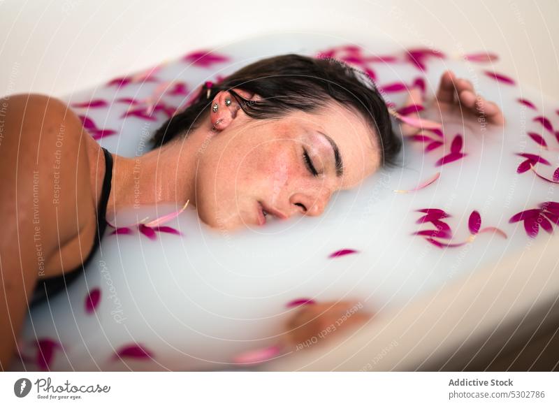 Calm woman taking bath with pink petals and milk flower bathtub peaceful hygiene spa skin care sensual female wellness rest chill sleep natural water fresh