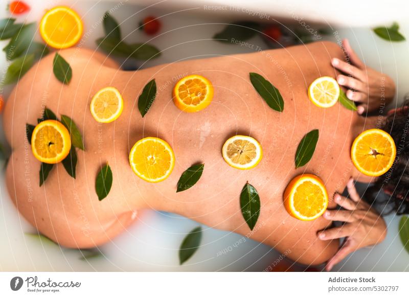 Crop woman with citrus slices on back lemon orange milk bath therapy care female treat recreation healthy skin care peaceful sensual fruit refreshment vitamin