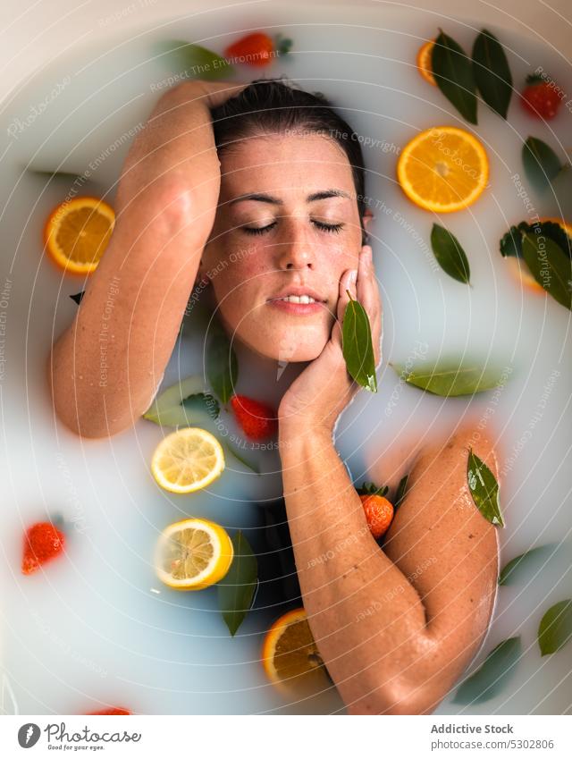 Woman taking bath with strawberry in mouth woman citrus orange slice milk eat wet hair spa female healthy rejuvenate procedure bathroom body care fruit water