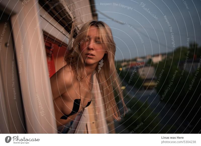It’s getting dark in the city. A view through the window. With a gorgeous naked blonde girl feeling wild and free. An erotic model test of a pretty young woman. Naked art with a touch of everyday life.