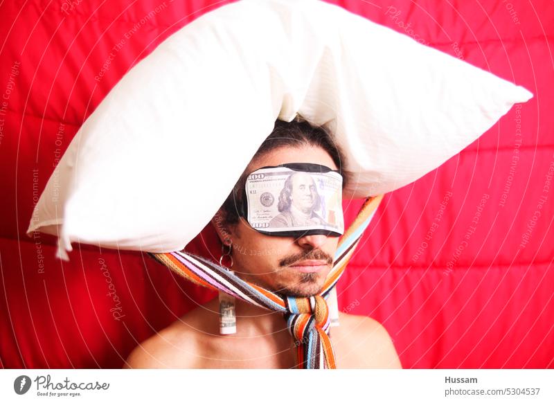 it is a photo concept a bout a person wearing a blindfold has dollar on it, and there is a pillow attached on his head. web money freelance dollars rich man
