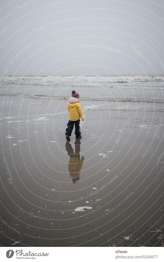 Child walking on Watenmeer beach in windy wet foggy weather Beach Wading Sea Sandy beach Fog Wind Cold Wet somber Damp Waves Foam Gray White Salty moody harsh