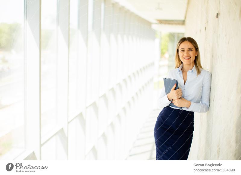 Young business woman holding with notebook in the office hallway professional modern female young smile businesswoman work lady corridor positive career