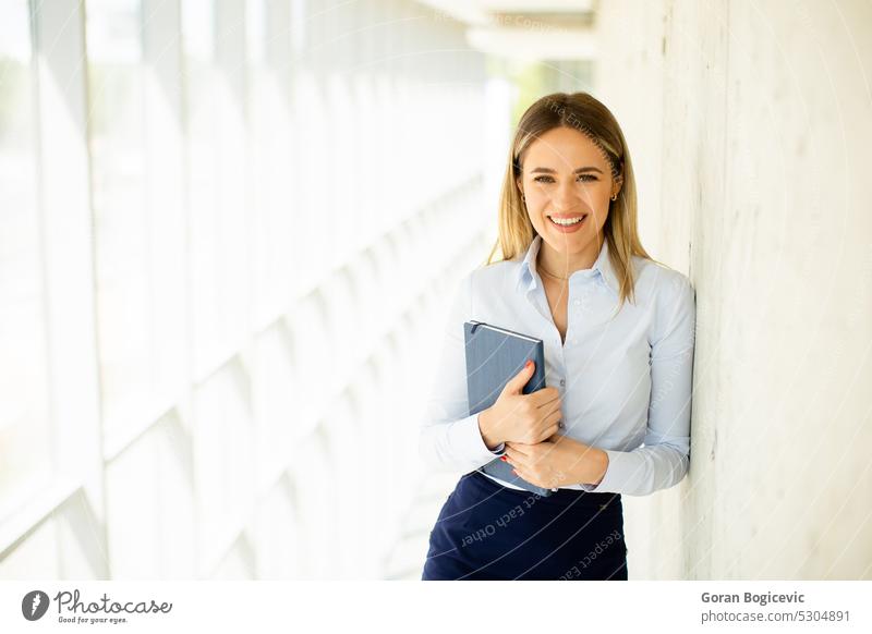 Young business woman holding with notebook in the office hallway professional modern female young smile businesswoman work lady corridor positive career