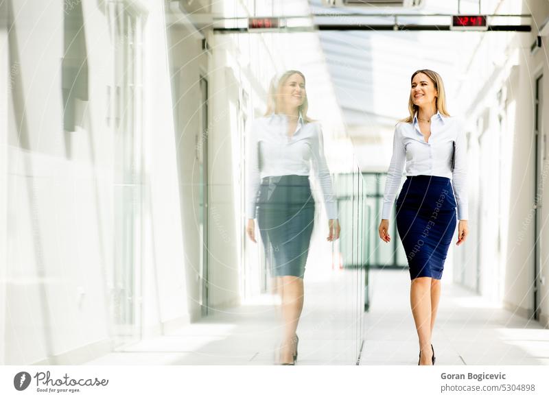 Young woman walking with digital tablet in the office hallway adult alone attractive beautiful beauty bright brunette business business person businesspeople