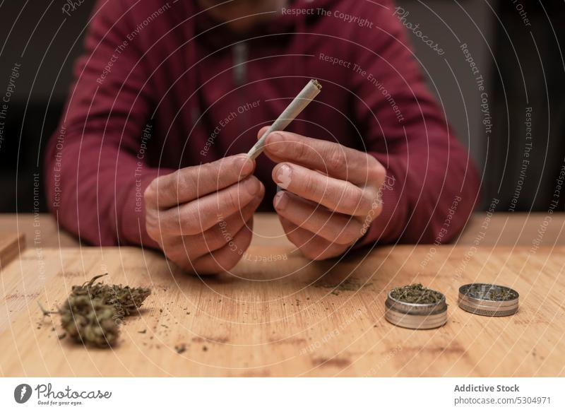 Anonymous man preparing joint for smoking cannabis marijuana weed drug roll blunt ganja smoker addict narcotic herb cigarette cannabinoid illegal cbd dope