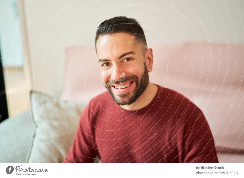 Smiling bearded man on sofa smile positive happy portrait rest comfort casual living room cheerful couch adult male home relax modern at home chill content