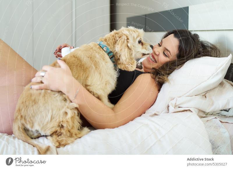 Happy woman embracing dog on bed smile stroke laugh caress pet relax bedroom happy lying cheerful underwear soft young morning lingerie comfort long hair home