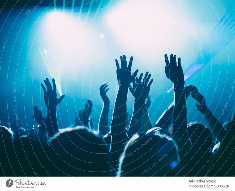 Hands of people on music show crowd raised hands concert blue light illumination party audience festival nightlife event entertainment performance fan club