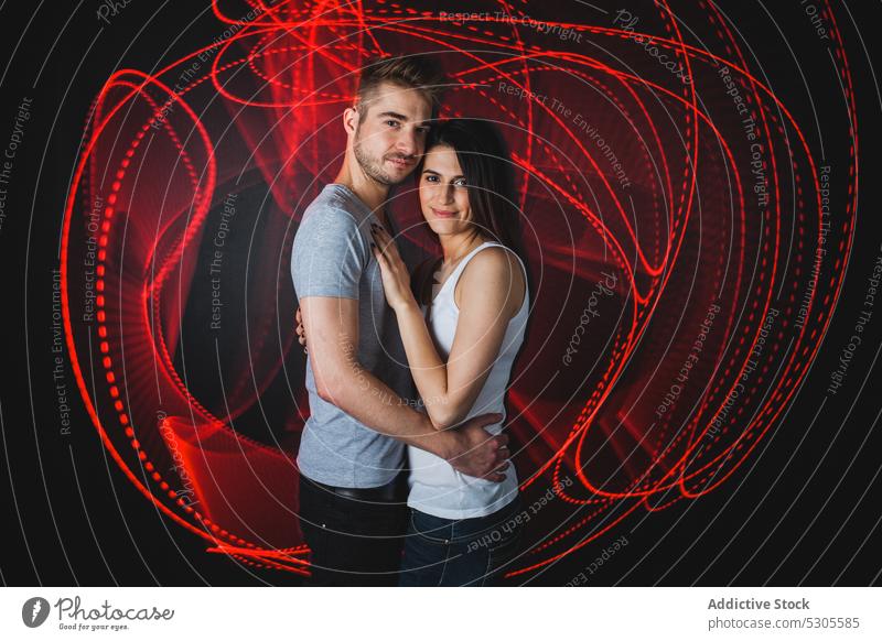 Couple near traces of light couple embraces young man woman casual love relationship together boyfriend trails hugging red bright vivid vibrant girlfriend