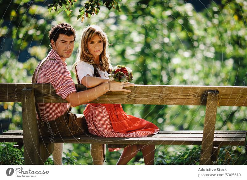 Couple in traditional clothing on bench couple sitting garden austrian smiling sunny daytime man woman park happy lifestyle leisure love costume outfit culture
