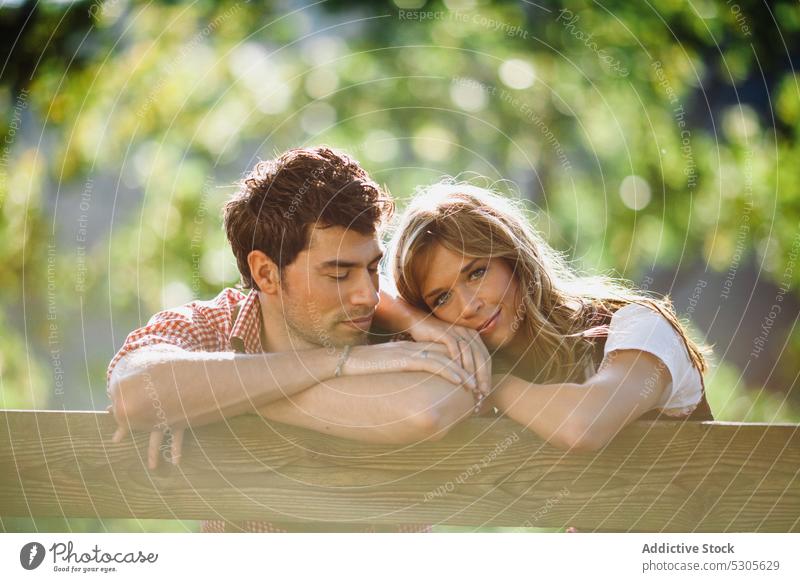 Couple in traditional clothes looking at each other couple sitting bench garden austrian clothing sunny daytime man woman park happy lifestyle smiling leisure