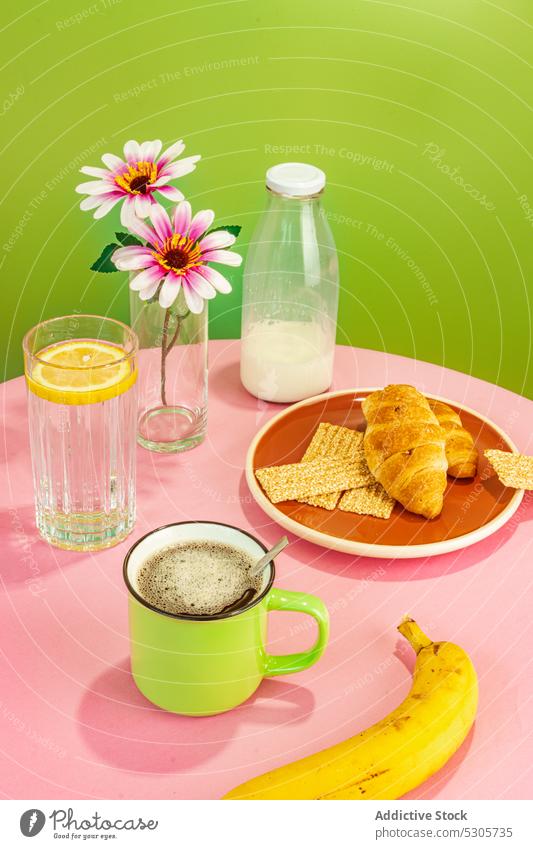 Delicious breakfast on pink table banana flower croissant beverage coffee water drink milk fruit lemon vase fresh cup bottle tasty delicious blossom morning