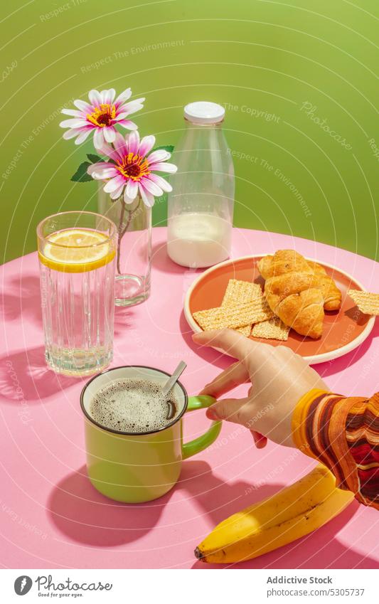 Crop person drinking cup of coffee breakfast croissant beverage morning flower milk banana delicious cream fresh tasty vase sweet table pastry yummy dessert