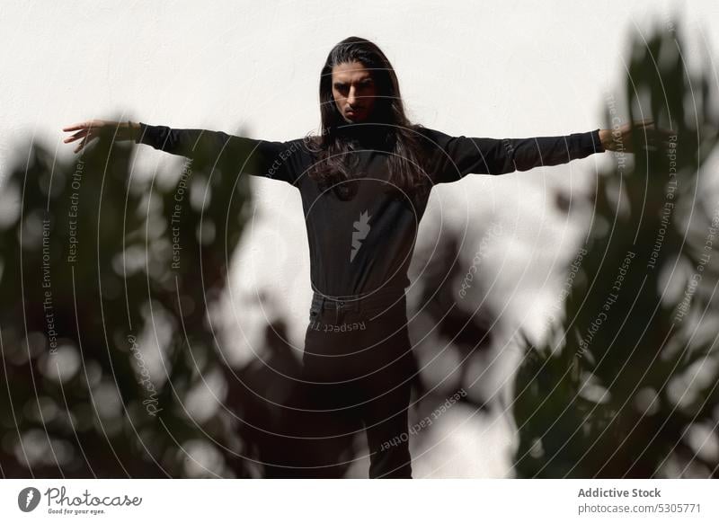 Carefree man with outstretched arms in studio model carefree long hair calm freedom style fashion enjoy appearance male individuality tranquil personality