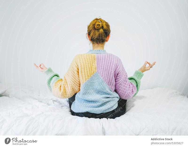 Unrecognizable woman with mudra hands on comfortable bed meditate calm yoga zen lotus pose relax gyan mudra sweater female bedroom cozy home tranquil knitted