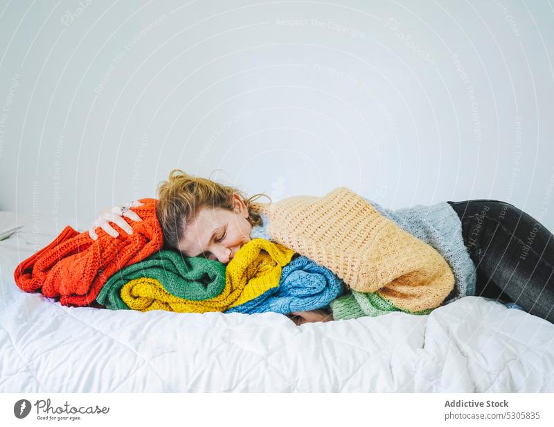 Relaxed woman lying on knitted sweaters on bed calm eyes closed comfort relax cloth home knitwear cozy bedroom soft pleased rest peaceful tranquil female young