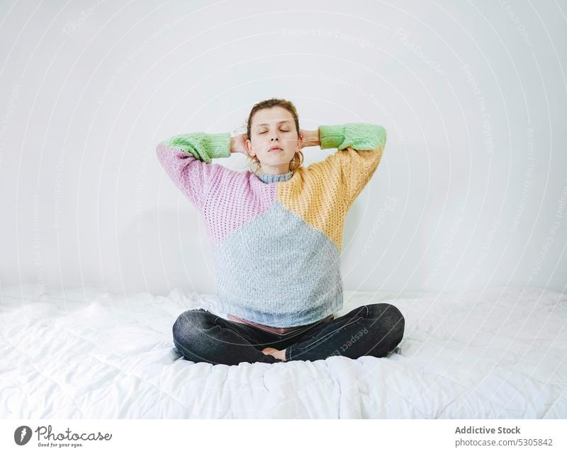 Calm woman meditating with closed eyes on bed meditate yoga lotus pose home calm relax padmasana eyes closed female zen peaceful young spirit bedroom tranquil