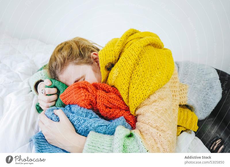 Relaxed woman lying on knitted sweaters on bed calm eyes closed comfort relax cloth home knitwear cozy bedroom soft rest peaceful tranquil female young serene