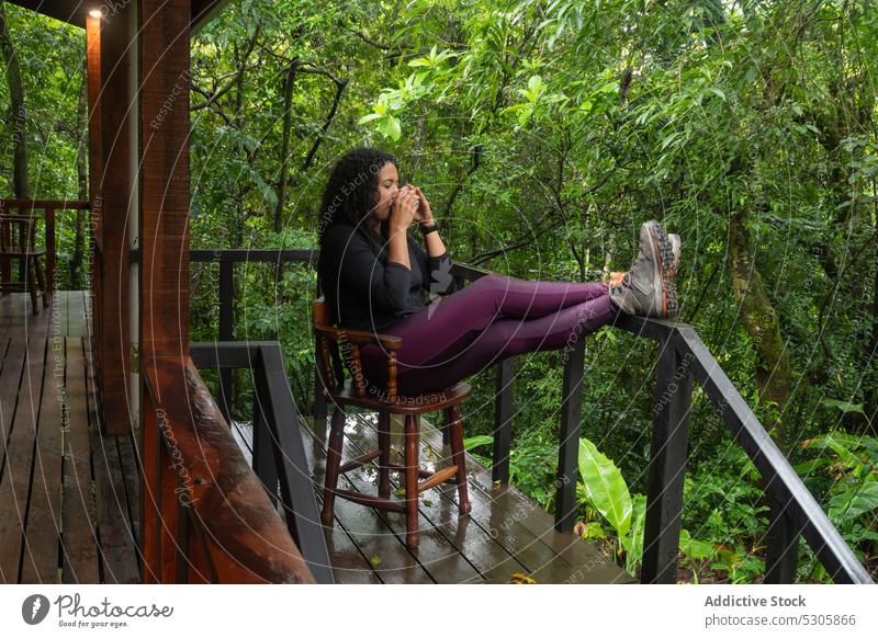 Relaxed woman drinking hot beverage in tropical forest chair vacation calm nature relax enjoy coffee wooden costa rica female cup hot drink tranquil chill trip