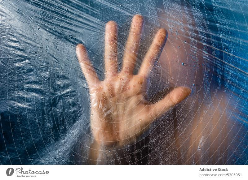Hand touching plastic film while standing behind it hand woman cellophane polyethylene anonymous environment helpless save eco protect female concept global