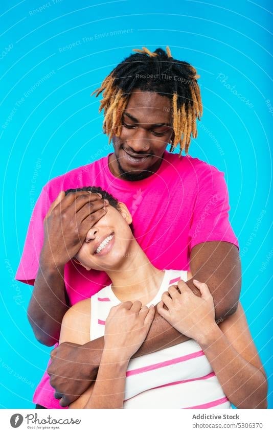 Cheerful multiethnic couple hugging in studio cover eyes embrace love together hide relationship boyfriend girlfriend cheerful smile having fun fooling around