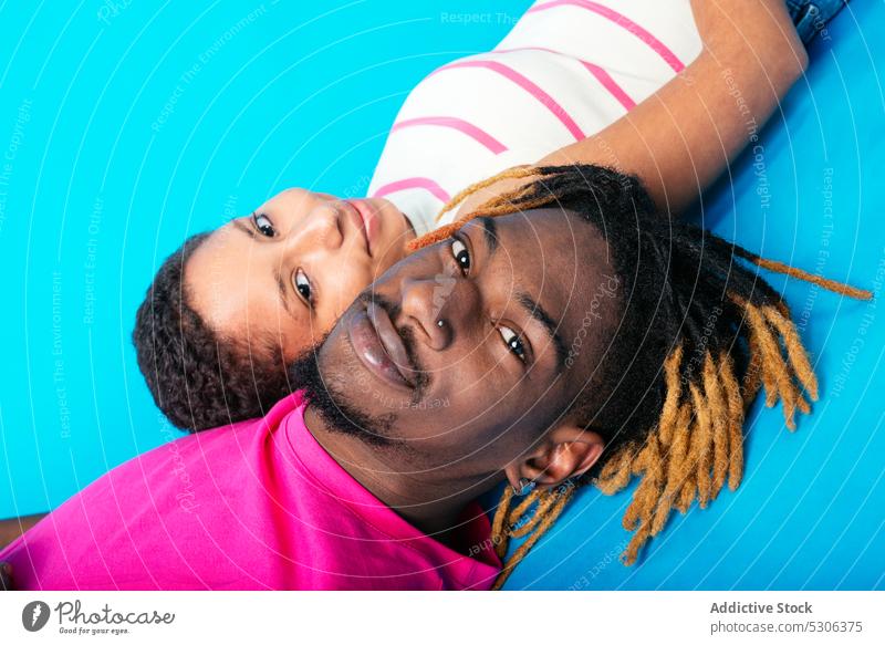 Diverse couple lying on blue background love harmony studio shot together beloved girlfriend boyfriend relationship multiracial multiethnic african american