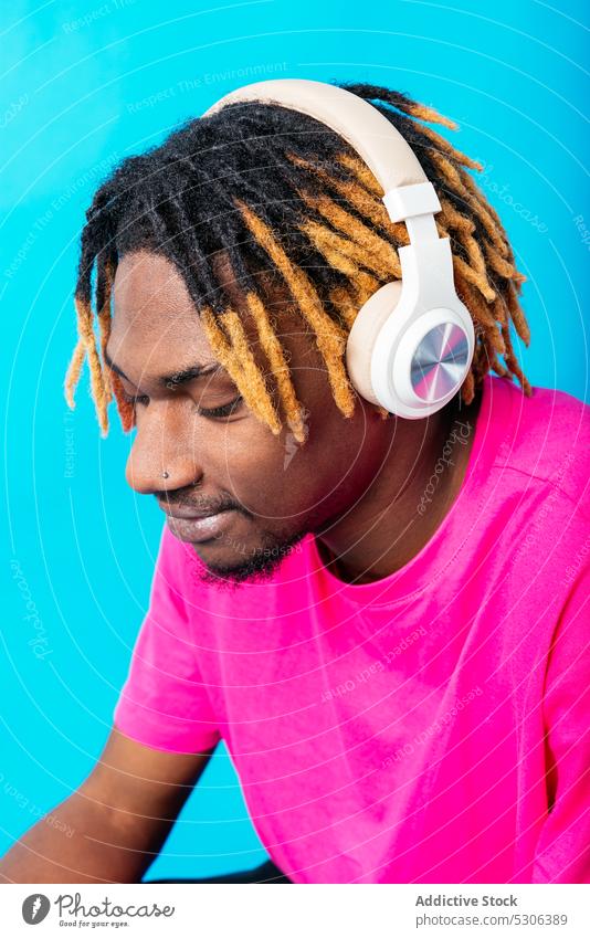 African American guy listening to music on headphones man touch audio song playlist melody studio shot male young african american black ethnic casual bright