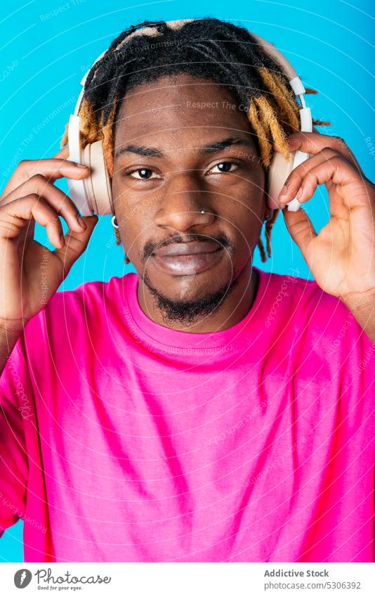 African American guy listening to music on headphones man touch audio song playlist melody studio shot male young african american black ethnic casual bright